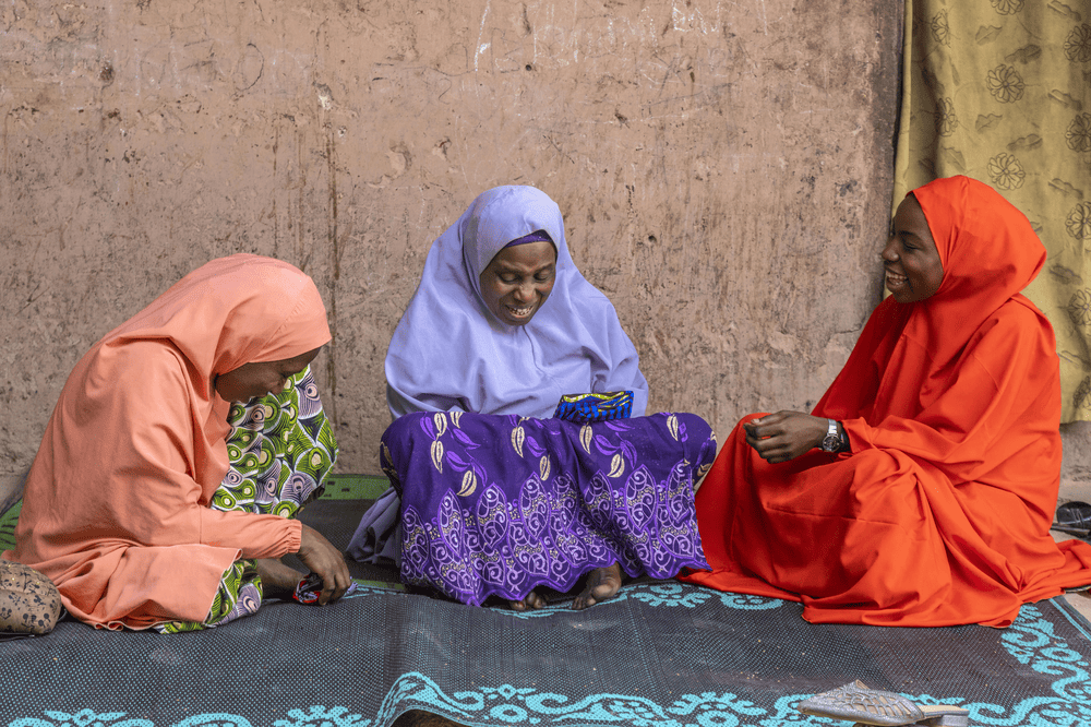 Teenage Rahamatu (right) sits with her mother Sakina (center) and grandmother Rahamatu (left).