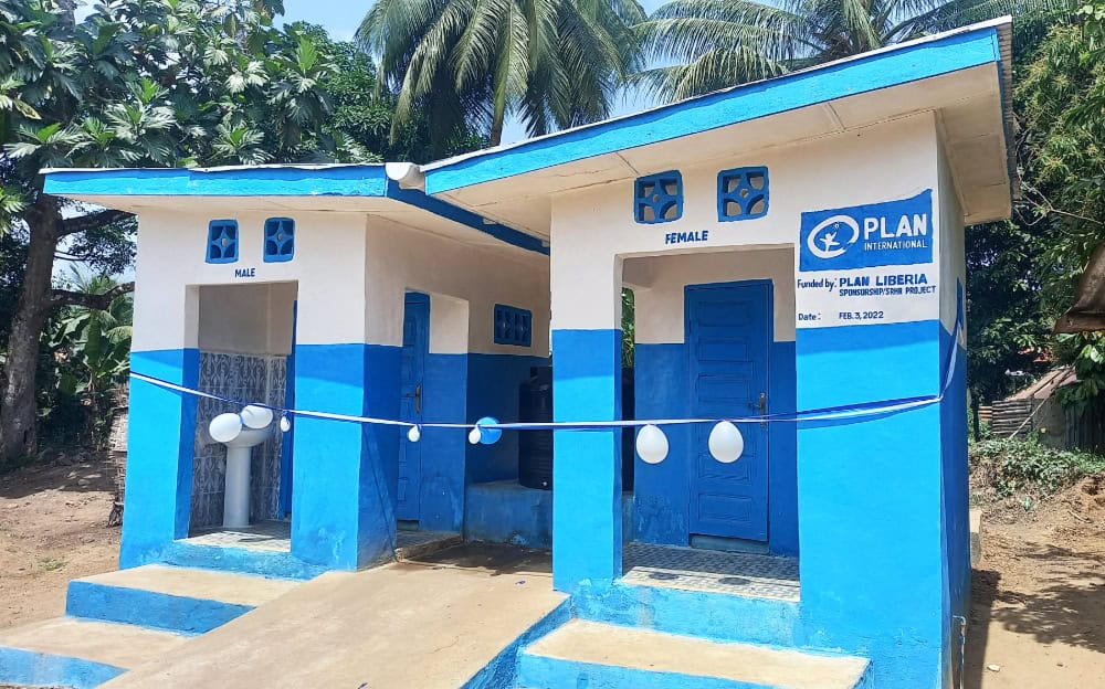 Blue and white concrete bathroom stalls with the designations "female" and "male" painted on their respective entryways.