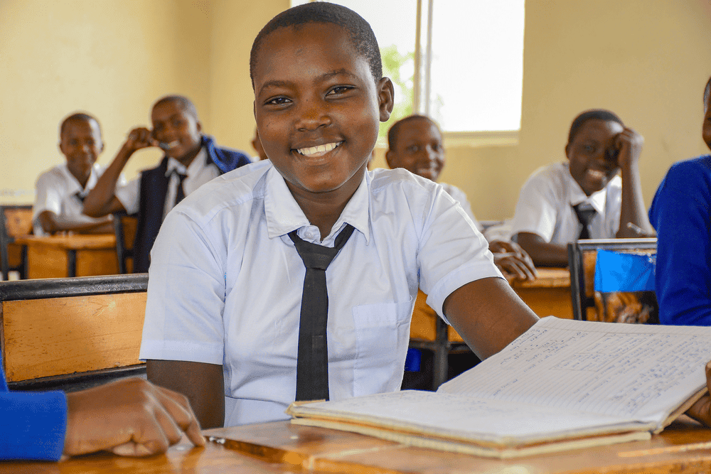 Close up shot of a smiling girl wearing a white button-up shirt and black tie.