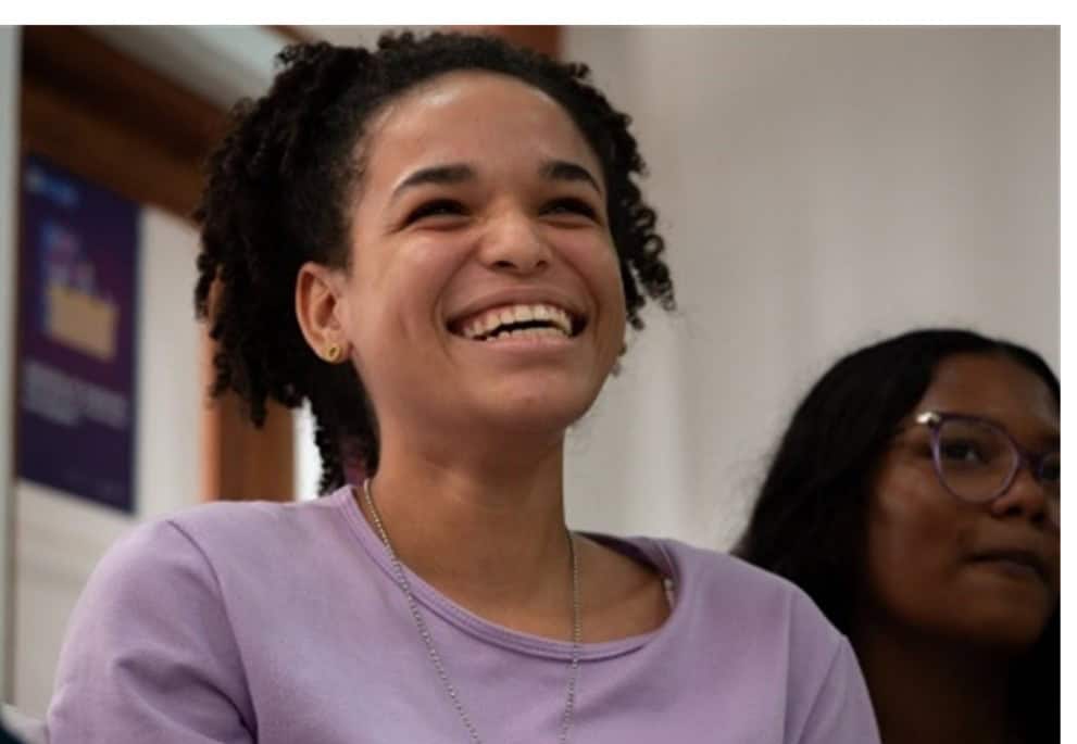 A girl in Peru smiles as she listens to someone speak.