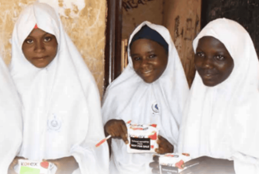 Girls in Nigeria hold up pads from their school’s pad bank.