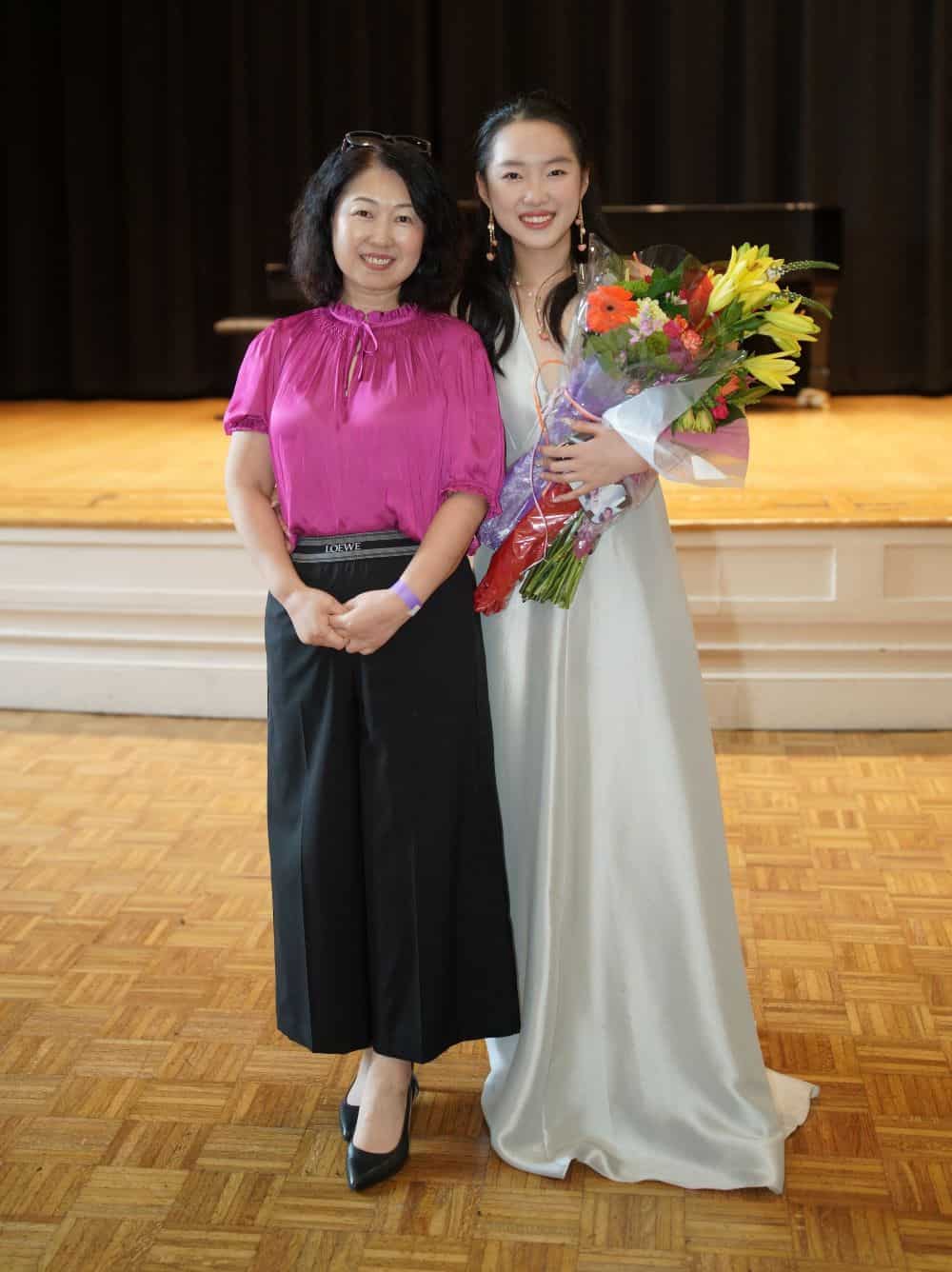 Sophia and her mother smile for the camera; Sophia holds flowers in her arms.