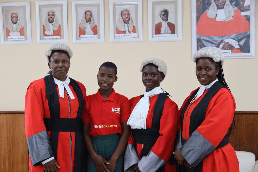 Two girls stand with women serving on the judiciary of Malawi's supreme court.