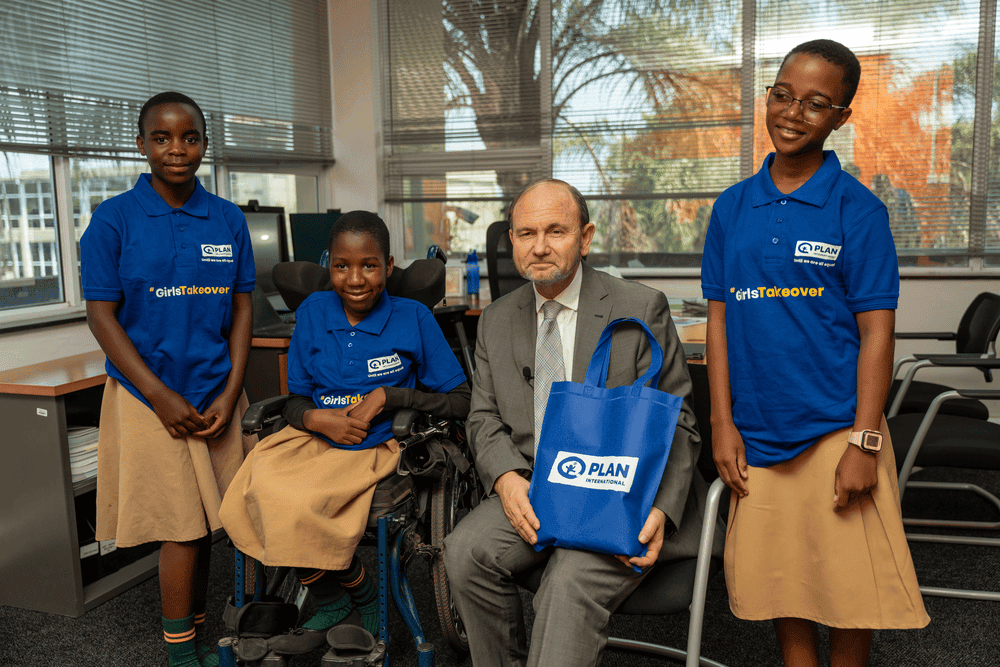 Peace, Chifuniro and Beatrice sit with Firas Raad for a photo.