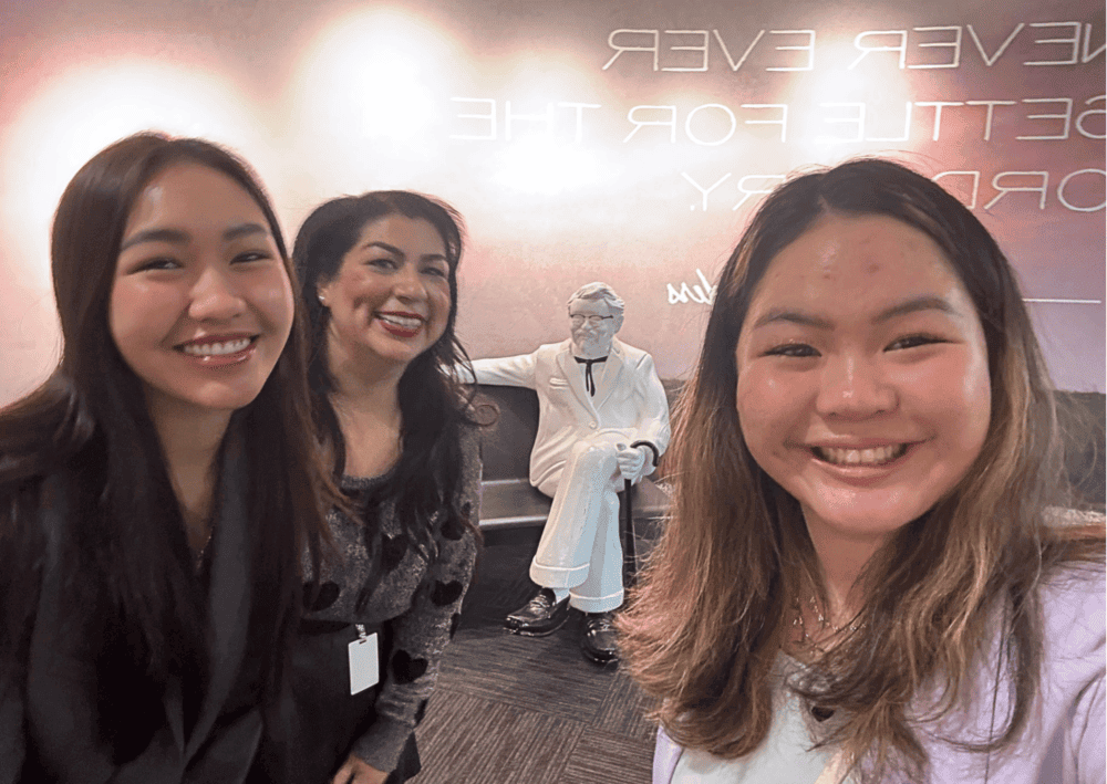 Pear and Shirlyn pose for a selfie with KFC's events manager and a statue of Colonel Sanders.