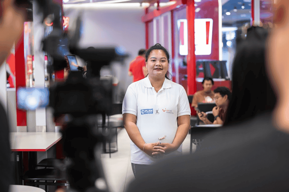 Sunisa stands in focus in front of camera equipment.