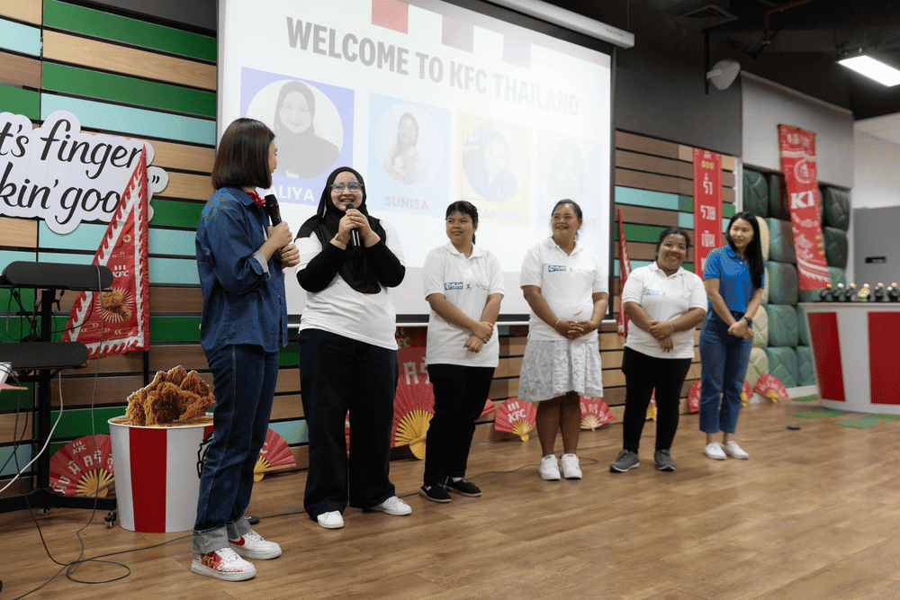 The young women in Thailand stand in front of a presentation to introduce themselves.
