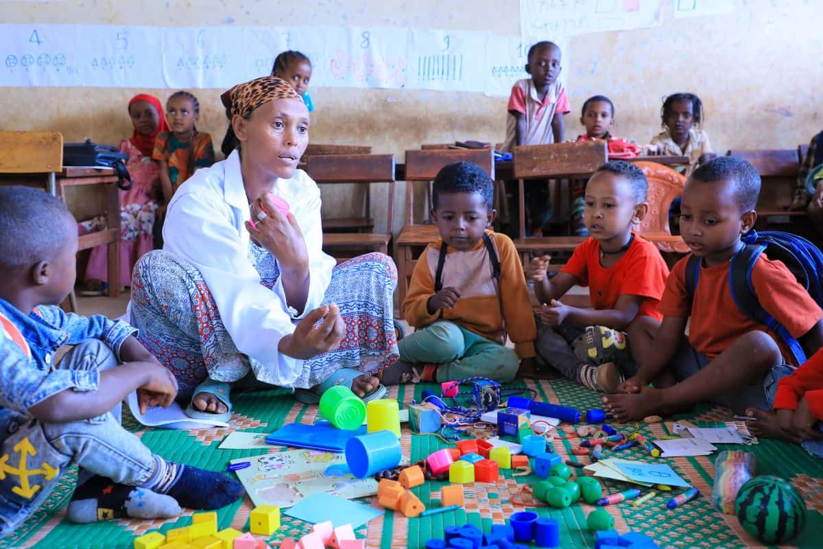 A teacher in Ethiopia leads a group of young children through hands-on play activities as part of Plan’s PlayMatters project, which supports learning and emotional development in refugee and host communities.