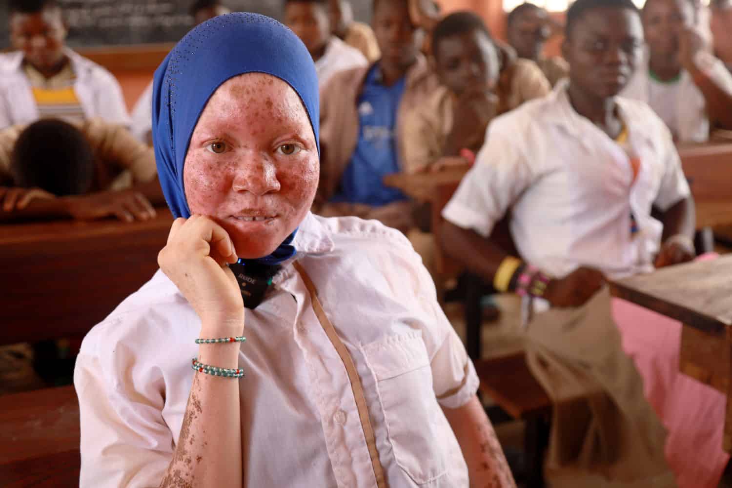 Rachidatou sits in class in northern Togo, smiling and looking directly at the camera.