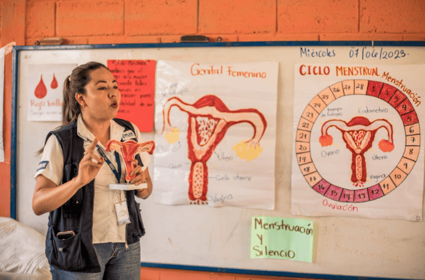 A Plan International staff member in Guatemala teaches a menstrual health lesson using anatomical diagrams to help girls understand their bodies and cycles. 