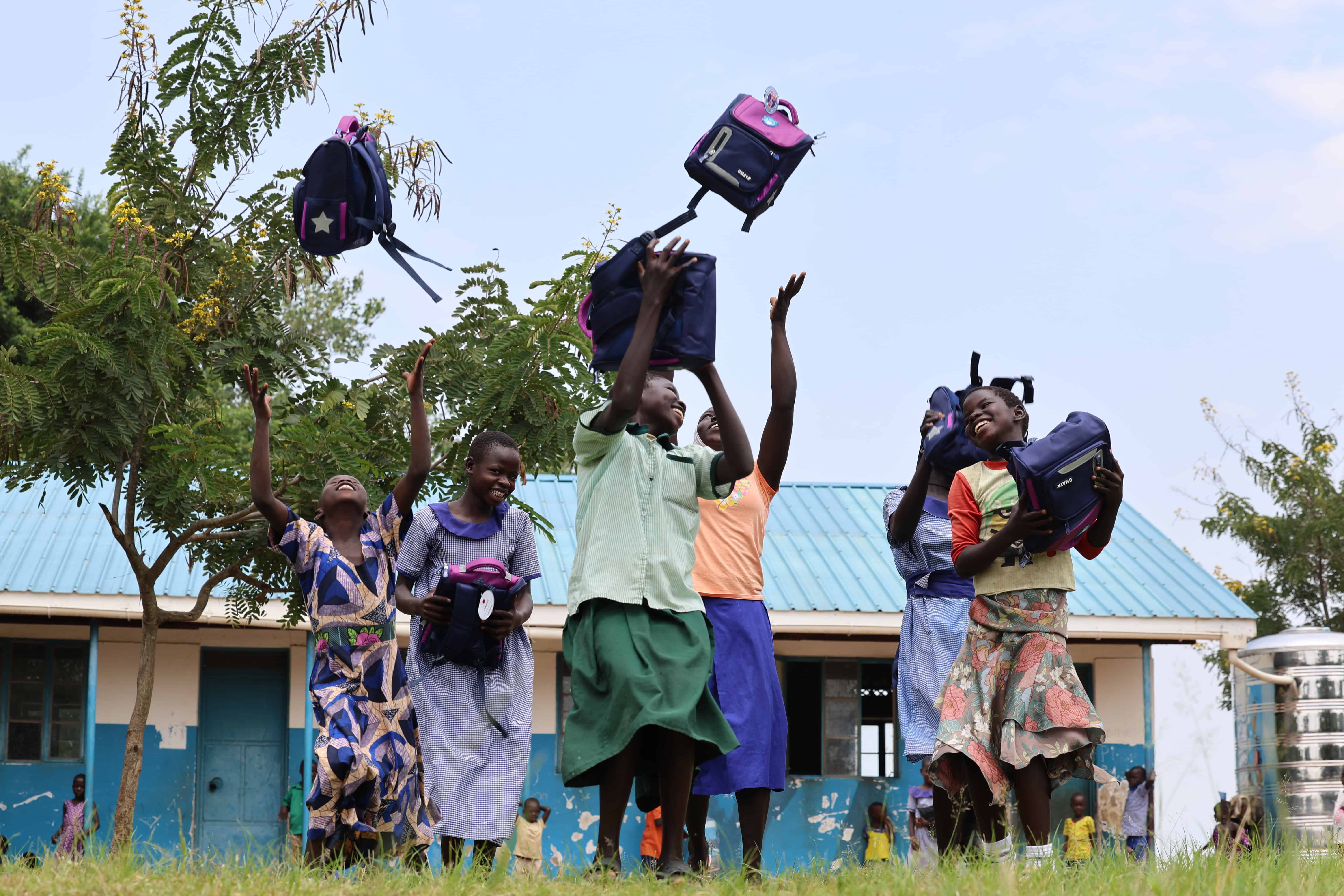 Students in Uganda jump for show as they receive their new Plan backpacks.