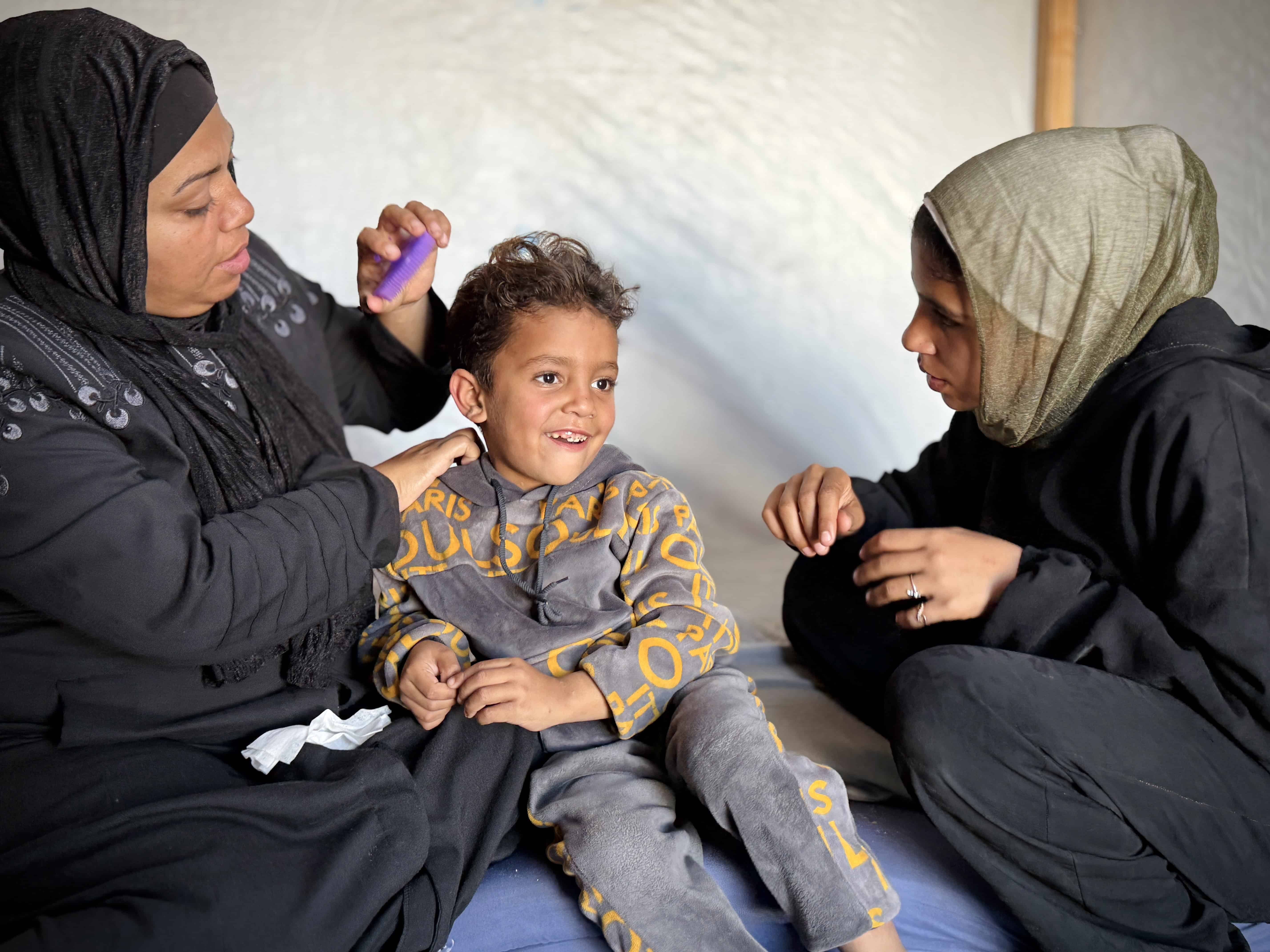 Latifah, a widowed mother of three, sits with her children in a crowded displacement shelter in Gaza.