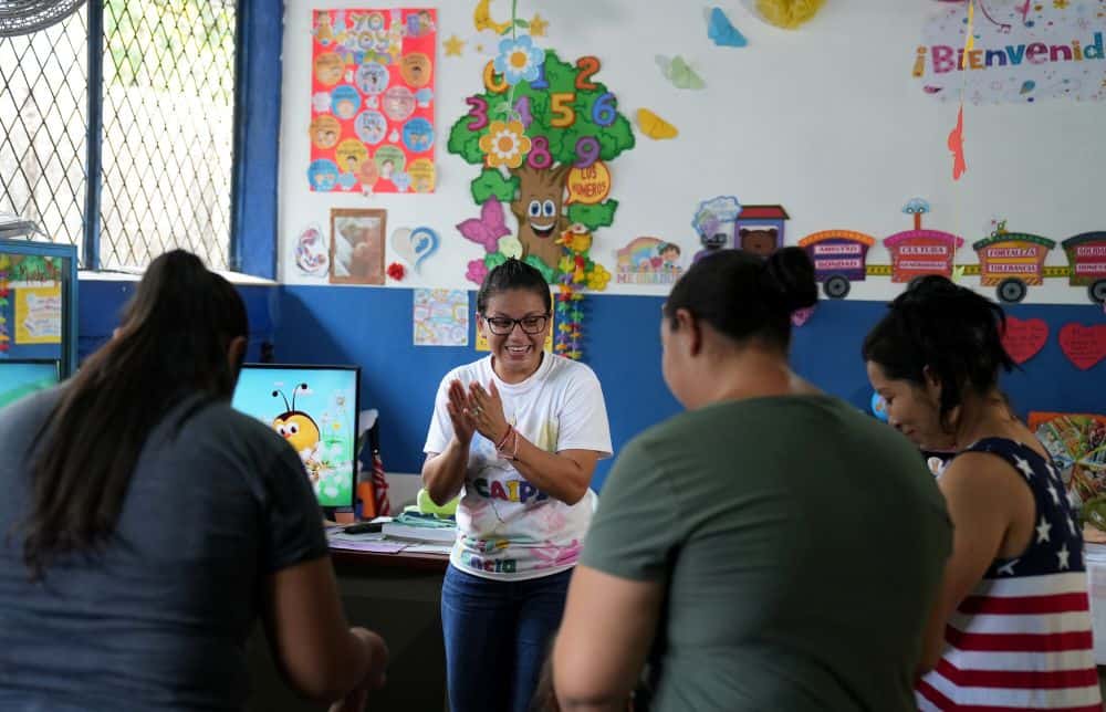 A group of women stand in a circle in Nancy's classroom.