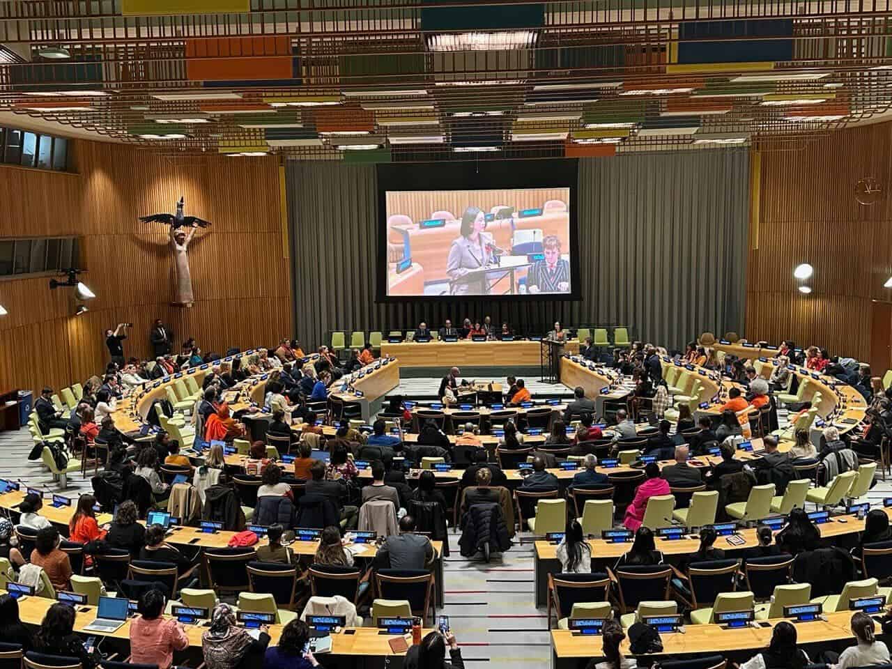 A full room at the United Nations listens as a young woman gives opening remarks during the Global Commemoration for the International Day for the Elimination of Violence Against Women