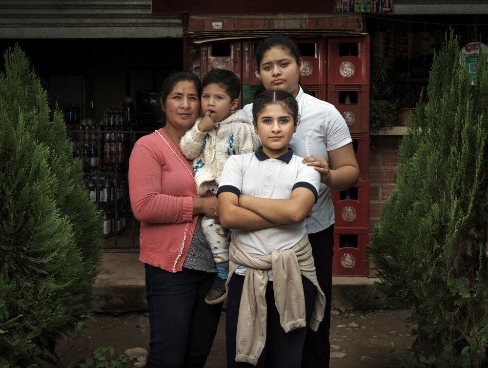 Dalita stands with her children outside their home in Bolivia