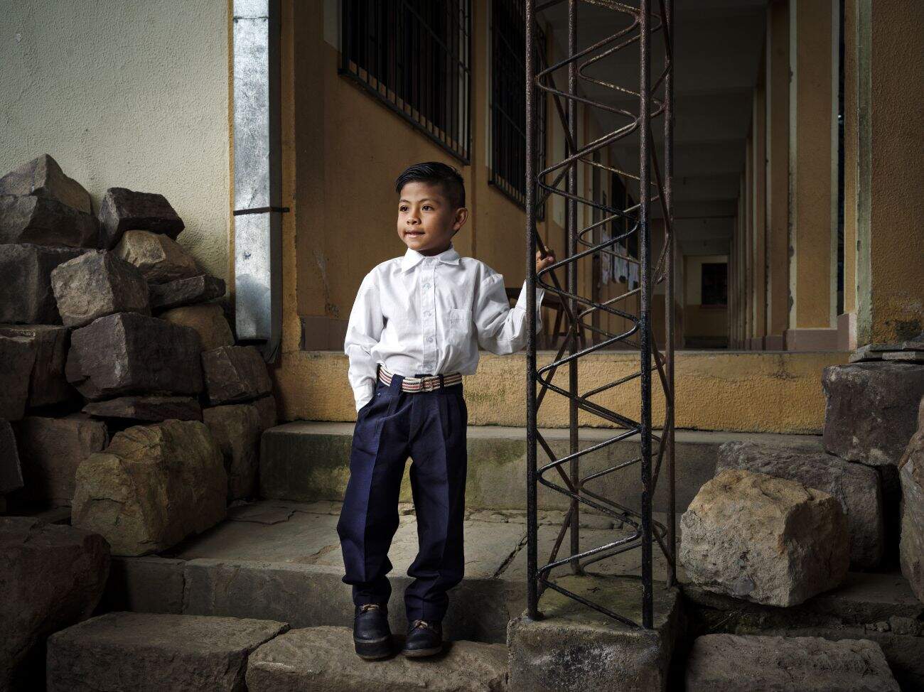 Gael stands outside his school in Bolivia, navigating uneven ground