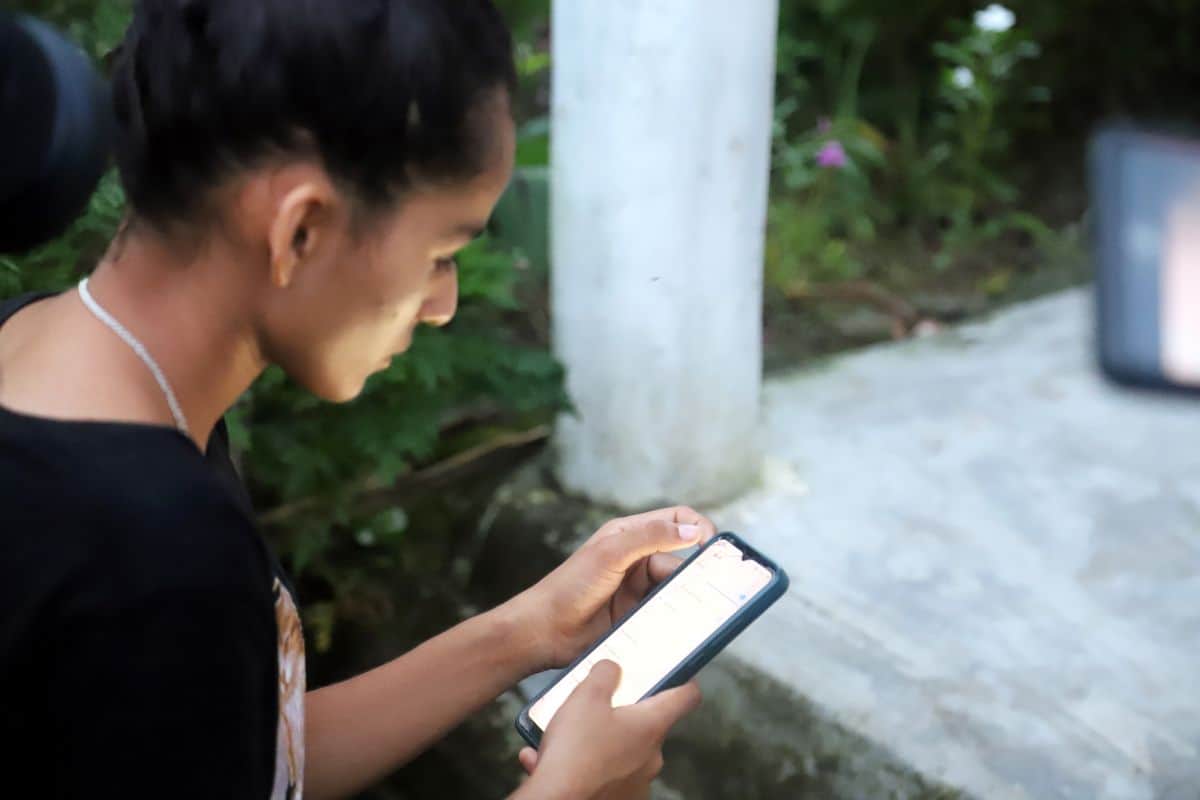 Regina using a mobile phone in Nepal to access online safety information.