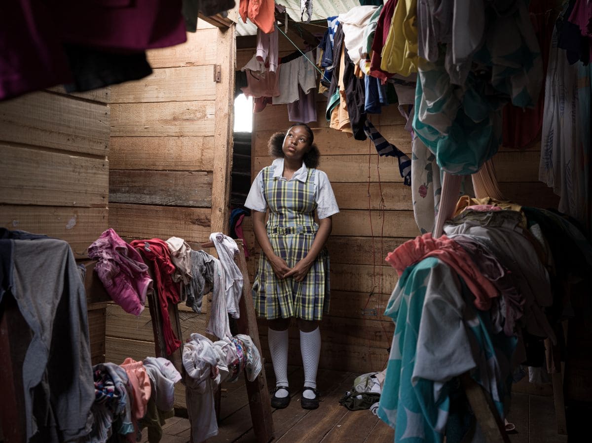 Yili, 16, standing inside her family home in Colombia surrounded by laundry.