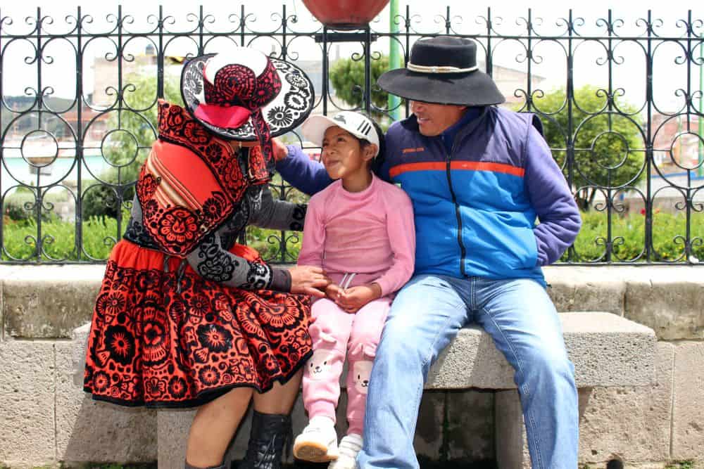 Jessica sits with her husband and daughter on a stone bench in Chumbivilcas, Peru.