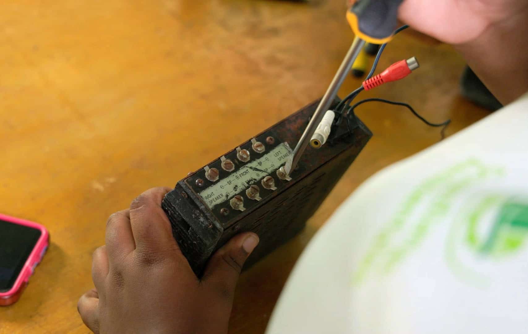 Close-up of a young woman’s hands working on an electrical component during a Solar Girls training session in the Dominican Republic.