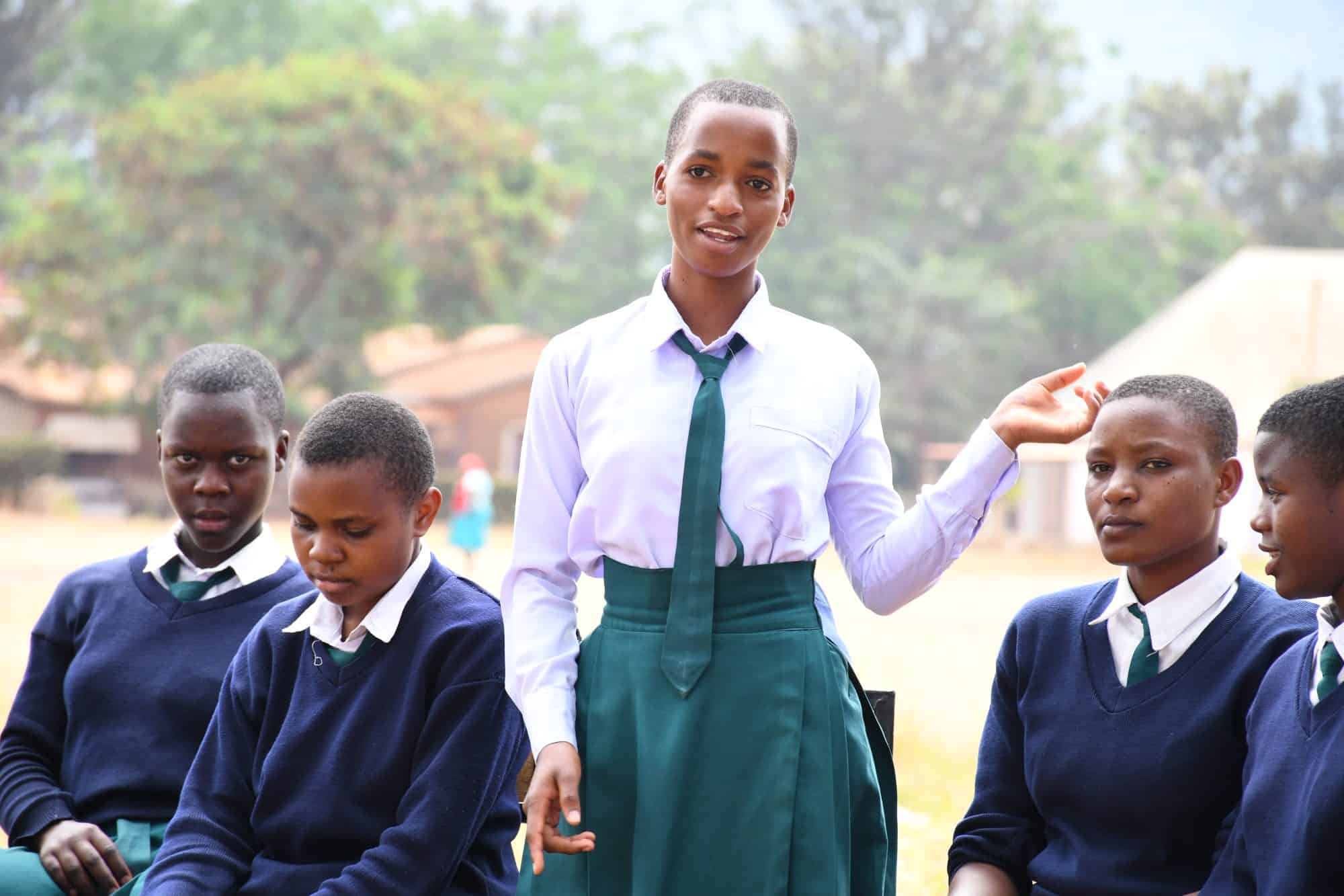 A girl in school uniform stands and speaks during an intergenerational dialogue session in Tanzania.