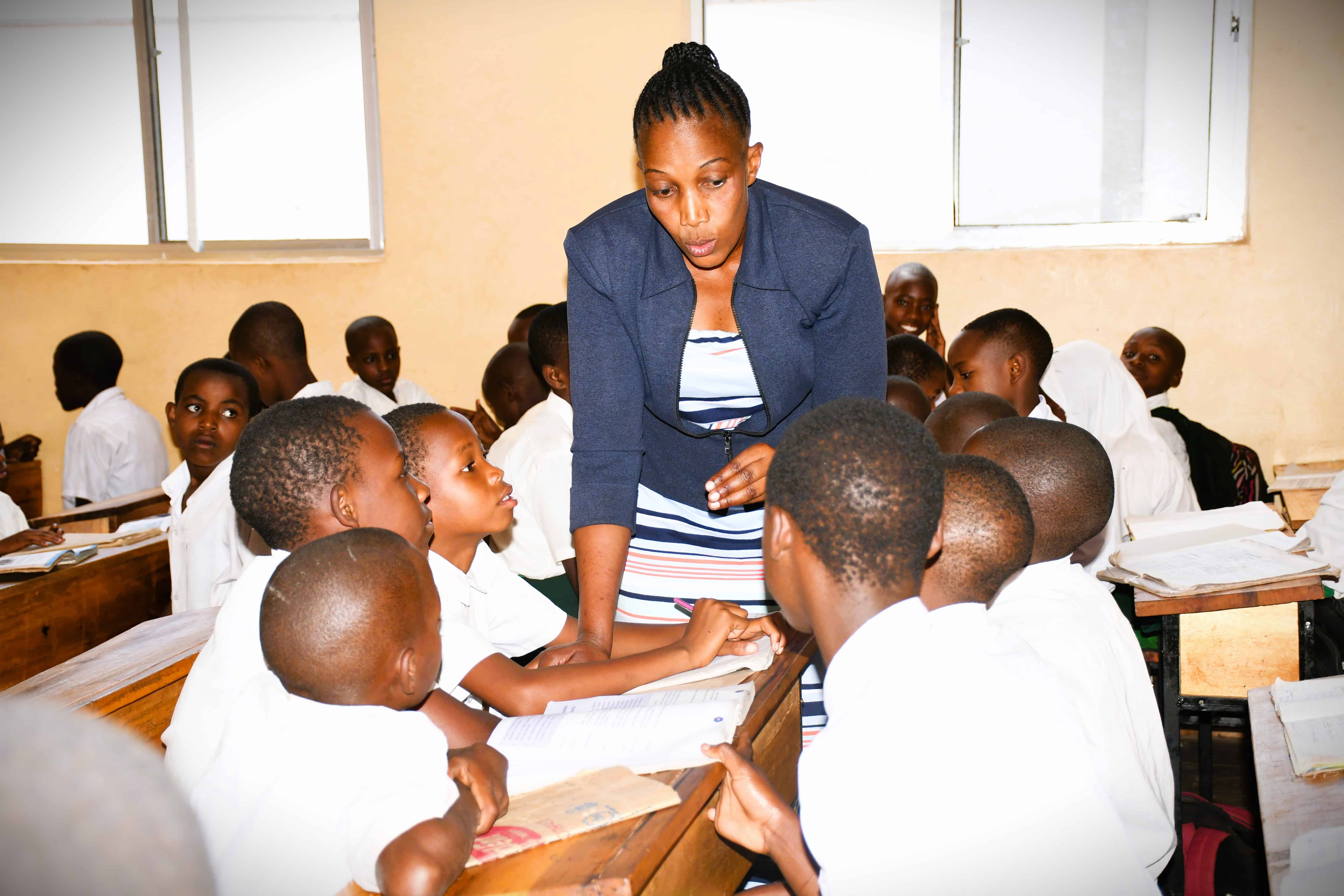 A teacher works closely with students during a group activity in a classroom in Tanzania.